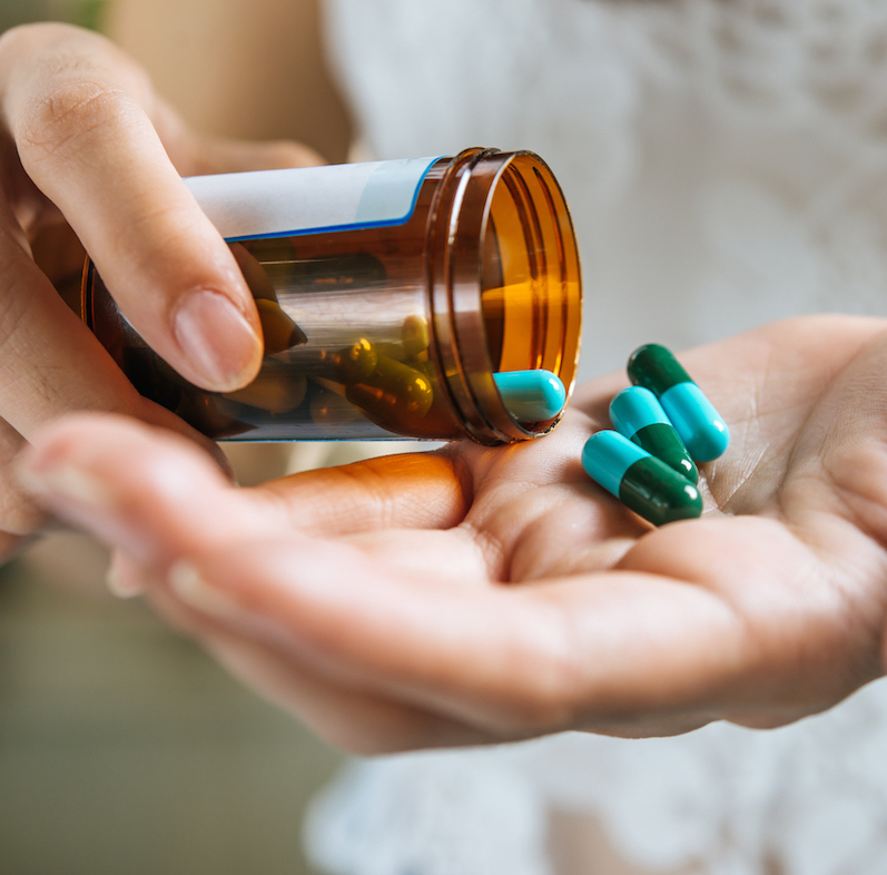 Woman’s hand pours the medicine pills out of the bottle SRS-Hair-Loss-Treatment